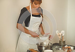 Woman adds some flour to dough on wooden table. Woman hands kneading fresh dough.