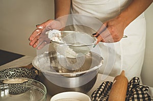 Woman adds some flour to dough on wooden table. Woman hands kneading fresh dough.