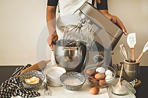 Woman adds some flour to dough on wooden table. Woman hands kneading fresh dough.