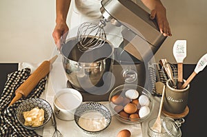 Woman adds some flour to dough on wooden table. Woman hands kneading fresh dough.