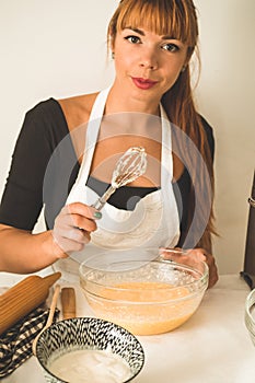 Woman adds some flour to dough on wooden table. Woman hands kneading fresh dough.