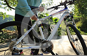 Woman adjust the seat lock of bike on forest trail