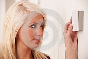 Woman Adjusting Central Heating Thermostat