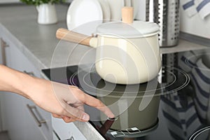 Woman adjusting electric oven cooktop in kitche