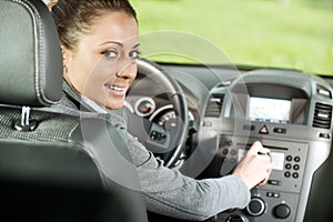 Woman adjusting radio volume in the car