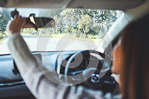 A woman adjusting a rear view mirror in the car