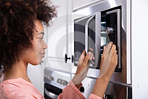 Woman Adjusting Temperature Of Microwave Oven