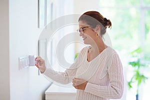 Woman adjusting thermostat. Central heating