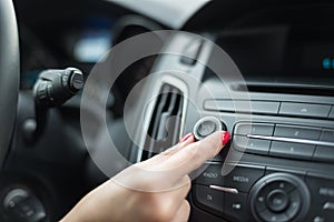 Woman adjusting volume on car radio