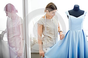 Woman adjusts dress on the mannequin