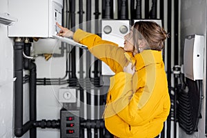 Woman adjusts heating temperature in the boiler room