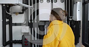 Woman adjusts heating temperature in the boiler room