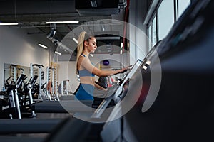 Woman adjusts speed to treadmill