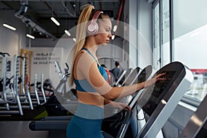 Woman adjusts speed to treadmill