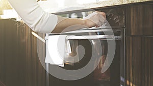 A woman adjusts temperature on the kitchen oven