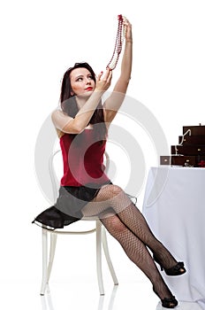 Woman admire jewellery in hand red corset chair white isolated