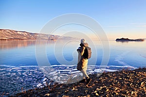 A woman admires the frozen Lake Baikal. Transparent ice.