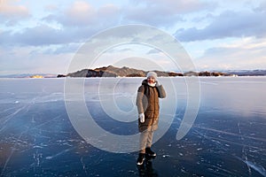 A woman admires the frozen Lake Baikal. Transparent ice.