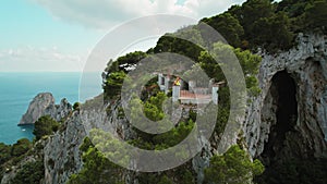 A woman admires the view of the Faraglioni stacks in Capri, Italy from a cliffside. Observation from the summit on