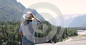 Woman is admiring beautiful view in mountains and drinking tea, back view.