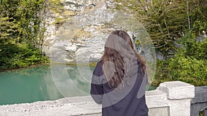 Woman admiring lake with green water and rocks walking in landscaped park.