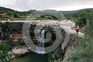 Woman admiring the landscape and walking next to a waterfall