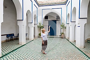 Woman admiring traditional moroccan architecture in one of the palaces in medina of Marrakesh, Morocco.