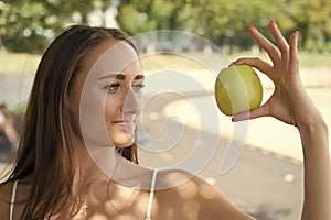 Woman adorable and healthy holds green apple. Secret of her beauty is healthy nutrition. Girl dieting or support