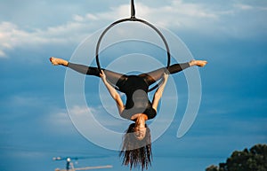 Woman aerialist performs acrobatic element split in hanging aerial hoop
