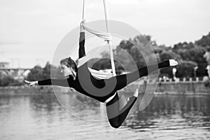 Woman aerialist performs acrobatic tricks on hanging aerial silk