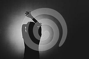 woman afraid of something, covering face and head with light behind