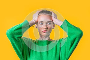 Woman afraid of something, she in shock on yellow backdrop.Holding head