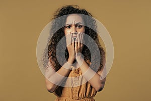 Woman afraid of something, she in shock on yellow backdrop. Shut mouth,screaming