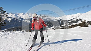 A woman afraid of a steep slope in the ski resort of side rises back leaning on the edge of the ski.
