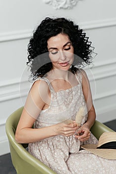 Woman with African curls in a dress sits in a chair