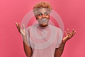 Woman of African descent looks excited happy on a pink background in the studio.