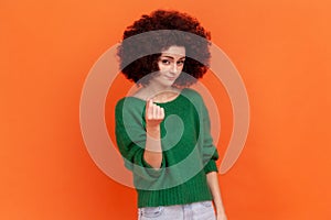 Woman with Afro hairstyle in green sweater rubbing fingers showing money gesture, asking for salary