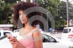 Woman with Afro style frizzy hair in the city during summer, bus