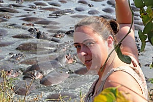 Woman against of herd of hippopotamus in water