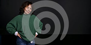 Woman age model. Beautiful adult woman in a green sweater on a black background.