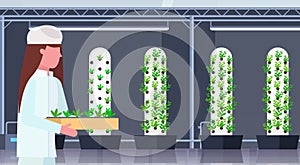 Woman agriculture engineer in uniform holding potted plants modern organic vertical farm interior farming industry