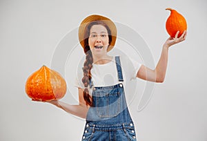 Woman of agriculture weighs a large and small organic pumpkin with her hands.