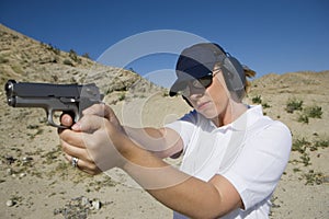 Woman Aiming Hand Gun At Firing Range In Desert