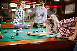 Woman aiming on pool ball while playing billiard