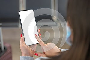 Woman at airport with her suitcase waiting air flight and holding smart cell phone in terminal departure lounge gate, traveler