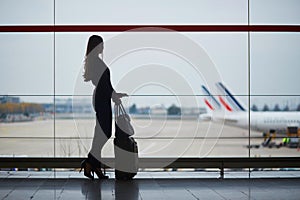 Woman in the airport, looking through the window at planes