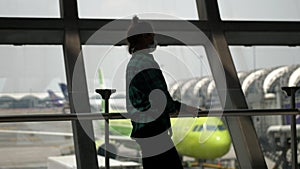 Woman at airport with wearing protective medical mask on the background of the plane waiting boarding time. Concept