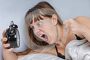 Woman with alarm clock comes late to work because she oversleep photo