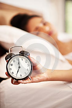 Woman, alarm and hand in bedroom, clock and tired or lazy in morning with noise alert in home. Hotel, ring and wake up