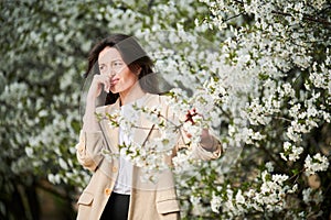 Woman allergic suffering from seasonal allergy at spring in blossoming garden at springtime.